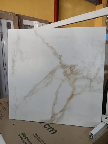 Porcelanato branco com veios dourados, tipo calacatta, exposto na loja